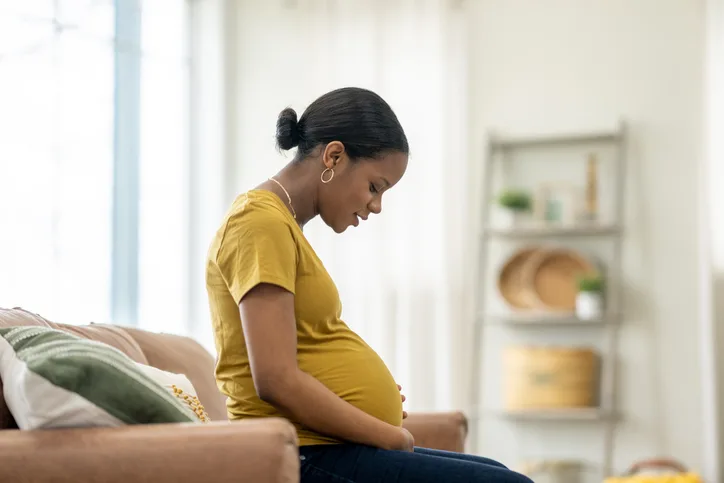 Pregnant woman sitting on the couch look anxious