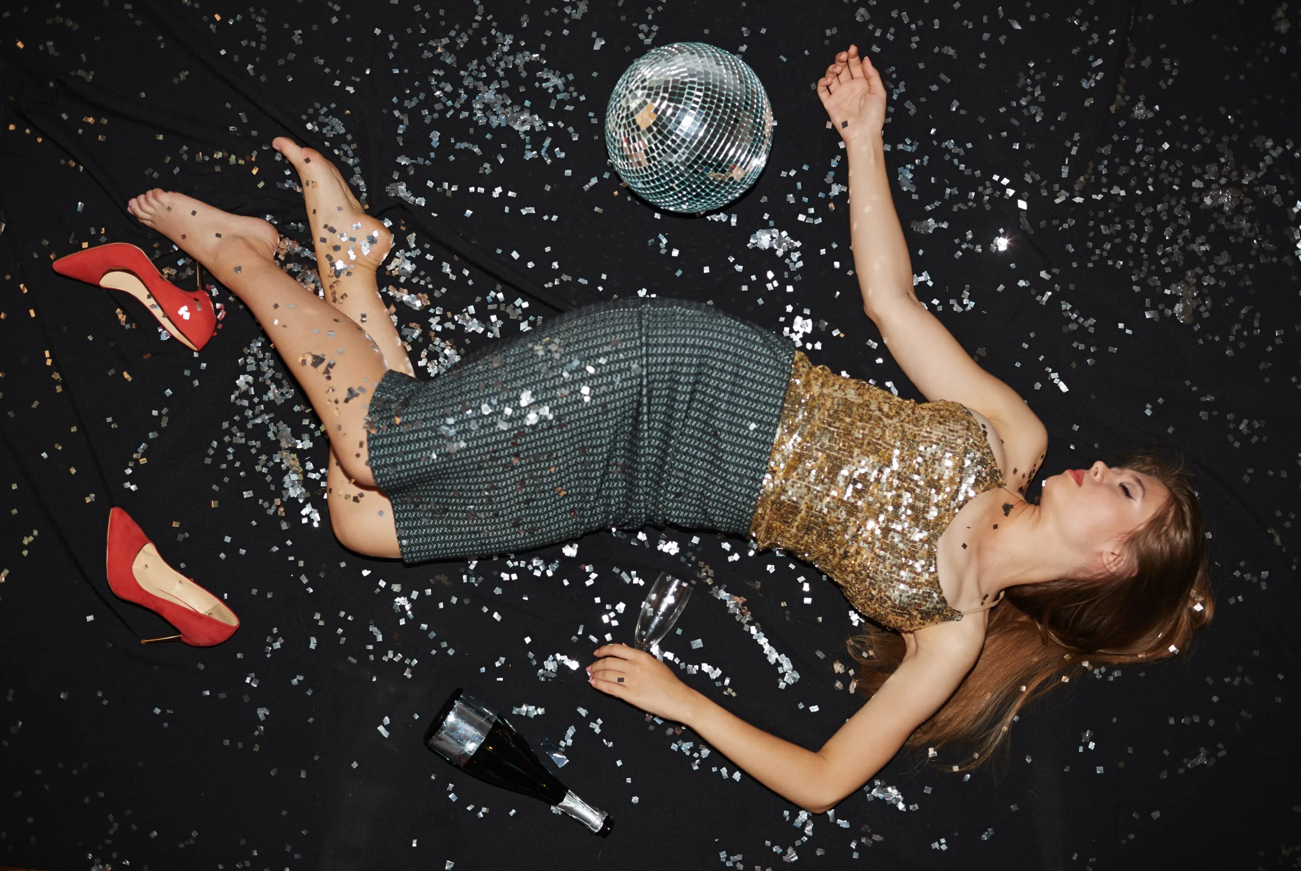 Drunk girl with empty bottle and flute sleeping on the dance floor