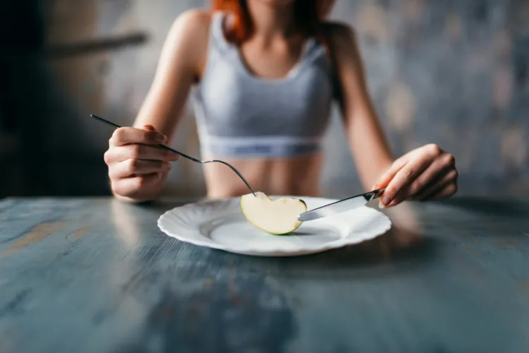 Female person against plate with a slice of apple. Weight loss diet concept