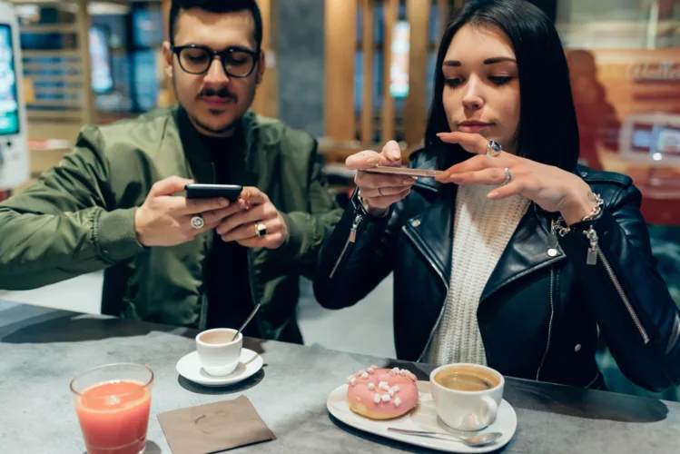 Young couple photographing food with smart phone - social network, sharing, food blogger concept